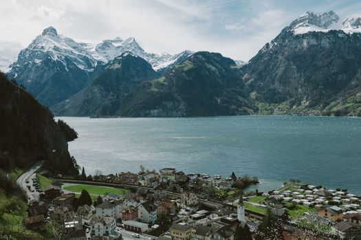 Scenic view of Lake Lucerne surrounded by Swiss Alps and a quaint village under a clear sky.