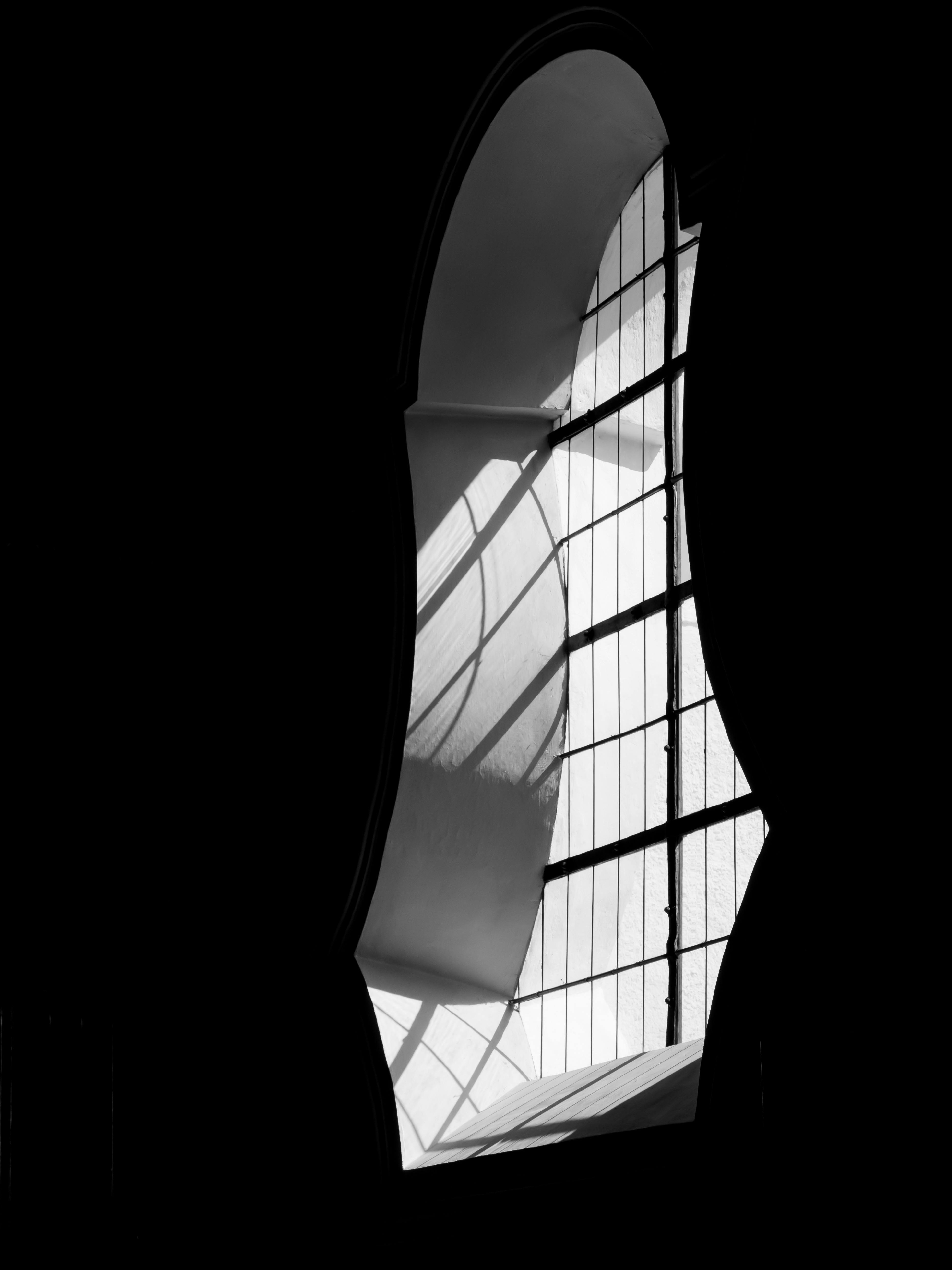 Striking black and white photo showcasing a modern interior with artistic window design, highlighting light and shadow play.