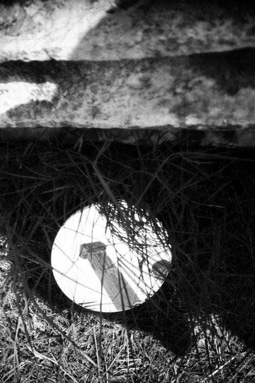Free A creative black and white image featuring a column's reflection in a round mirror surrounded by grass. Stock Photo