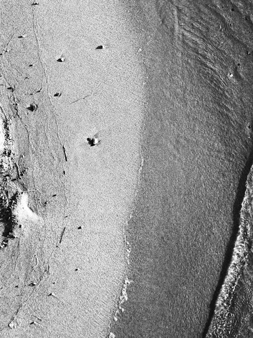 A black and white photo of a beach with a person walking on it