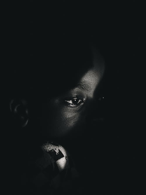 A black and white photo of a child looking into the dark