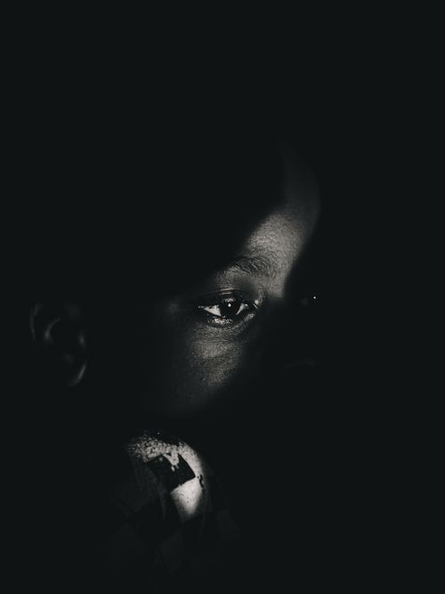 Free A striking black and white close-up portrait of a child's face in shadow. Stock Photo