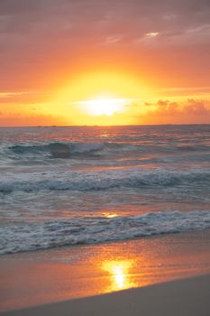 A stunning sunset over the serene beach in Punta Cana, Dominican Republic, with waves gently lapping at the shore.