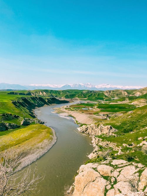 A river flowing through a valley with mountains in the background