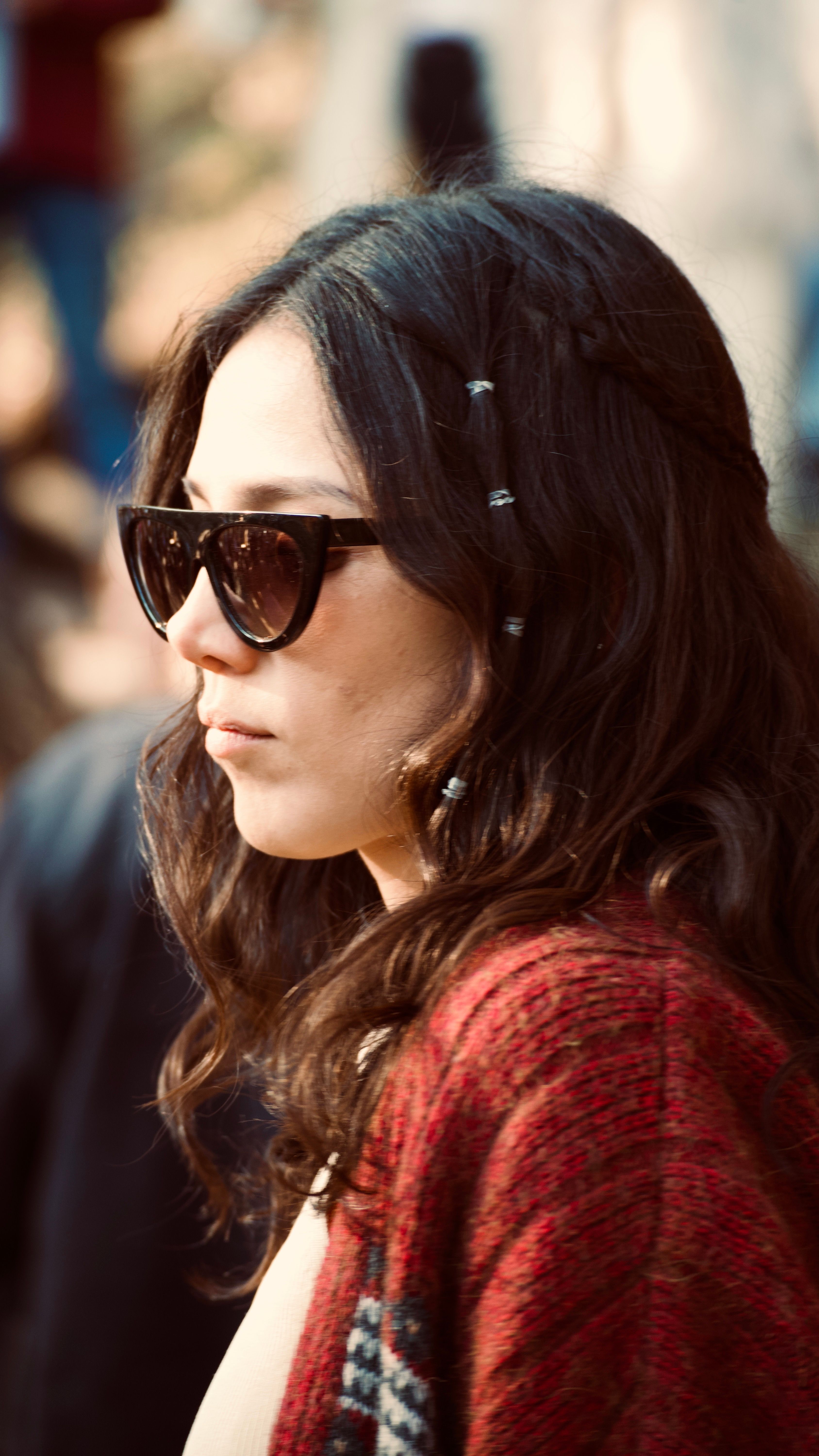 Profile of a stylish woman wearing sunglasses with braided hair outdoors in natural light.