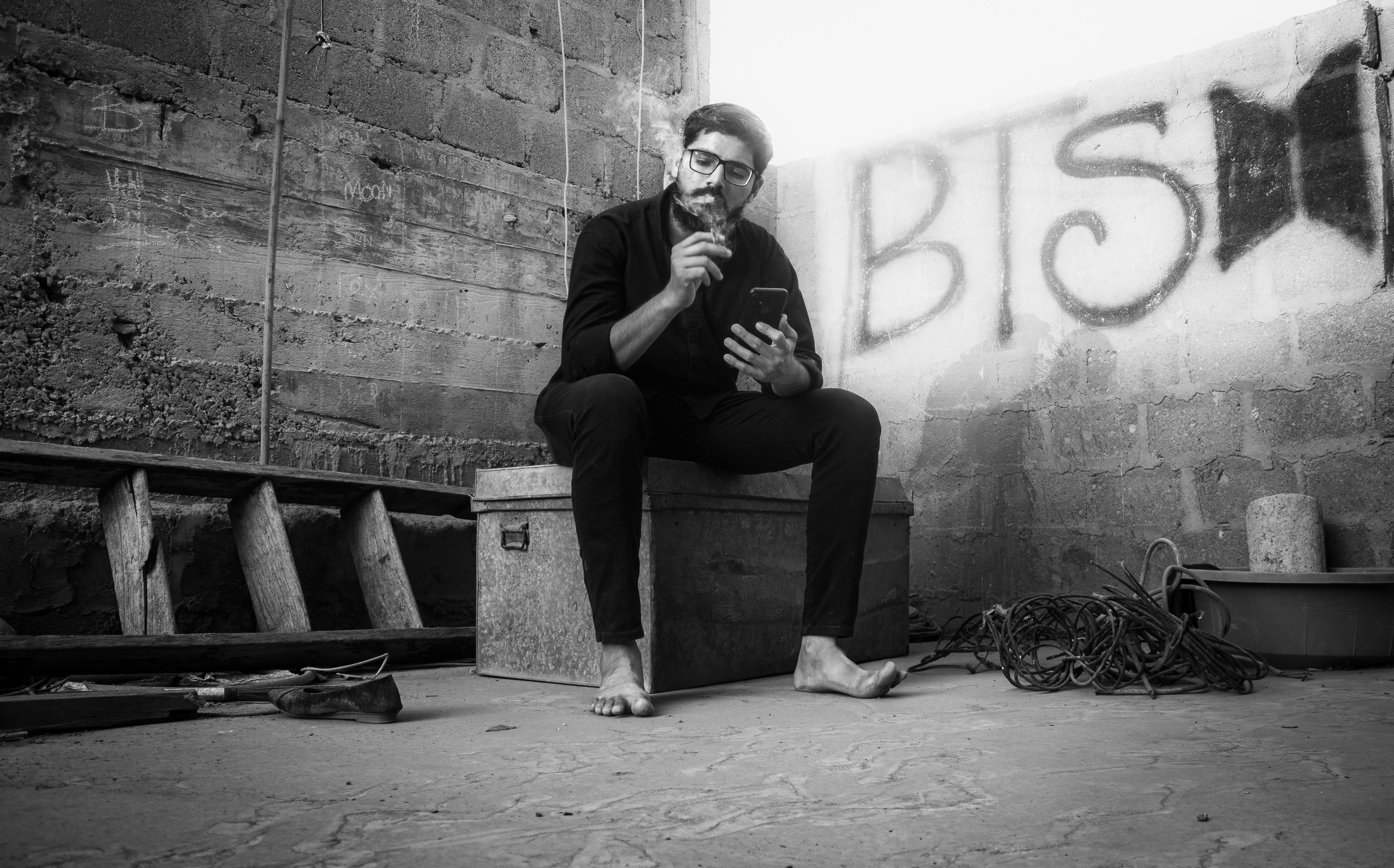 man sitting with smartphone in corner and smoking