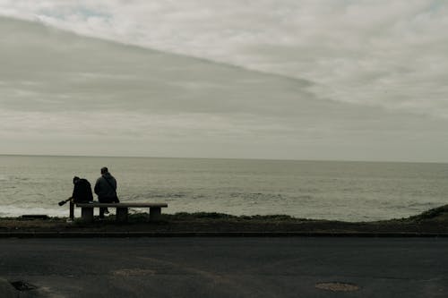 Father and son talking sitting by the ocean