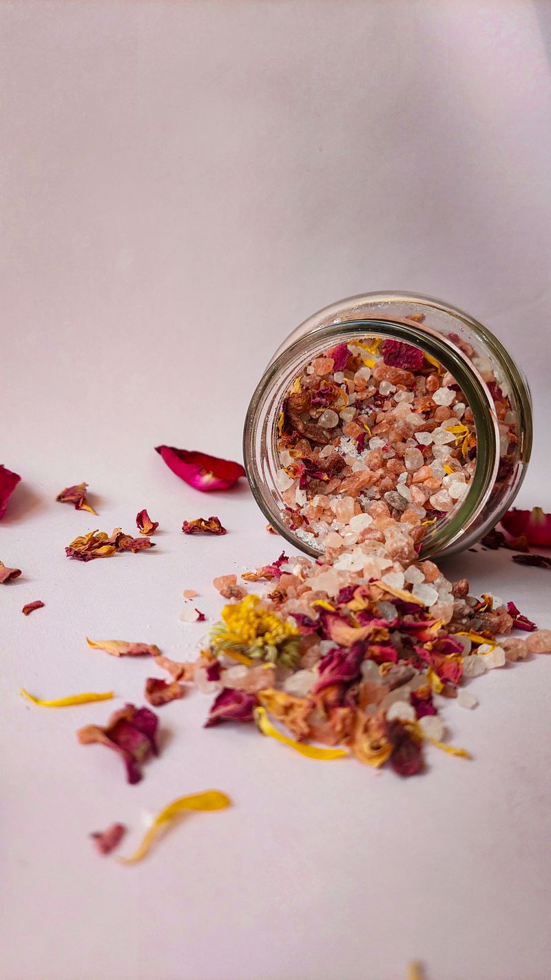 Glass jar of aromatic bath salts mixed with dried flowers