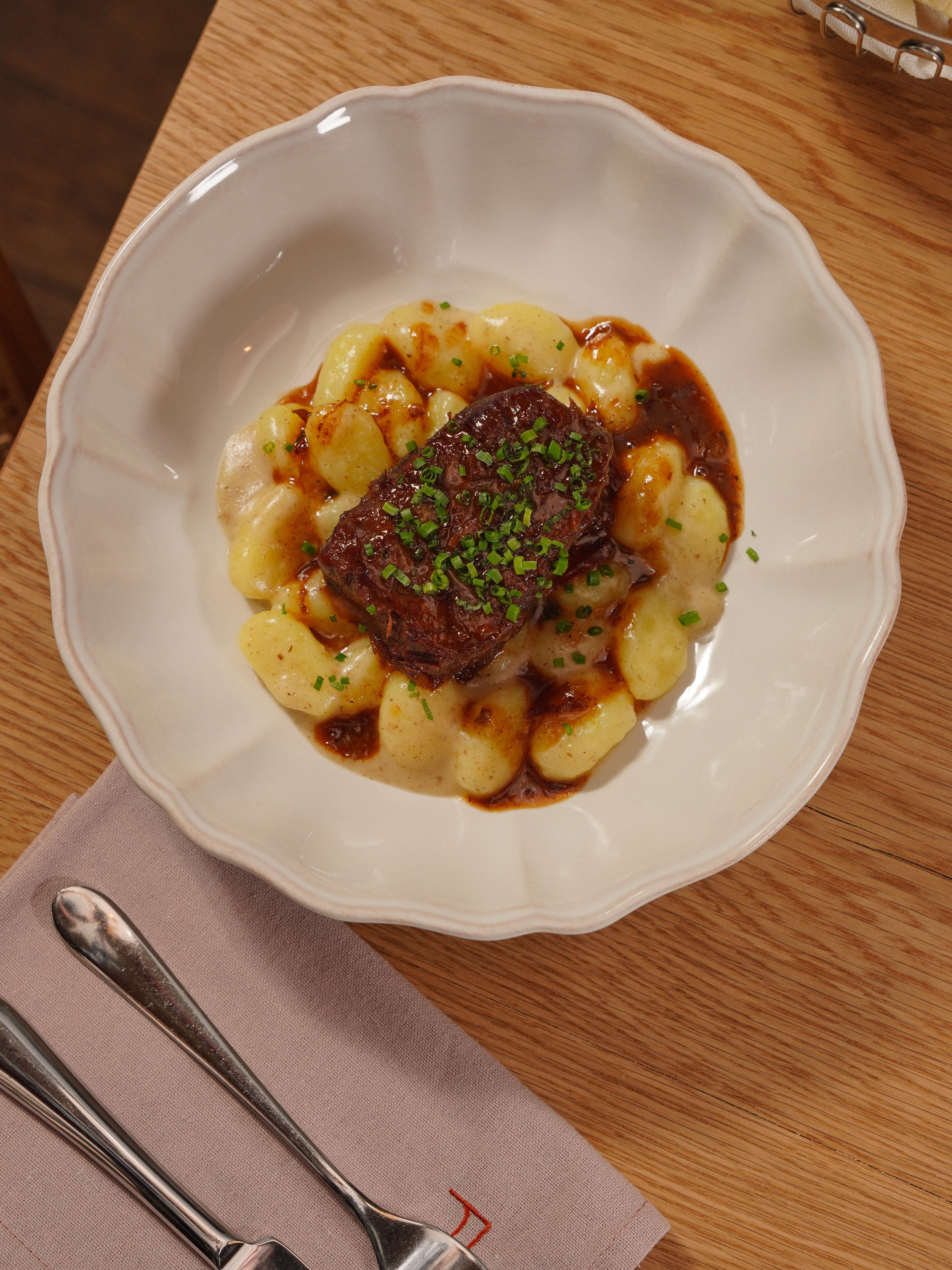 Seared steak served over gnocchi with a rich brown sauce and fresh herbs