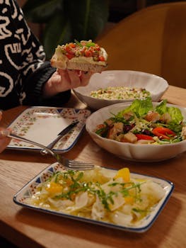 A cozy indoor setting featuring a healthy meal, including salads and a sandwich being enjoyed.