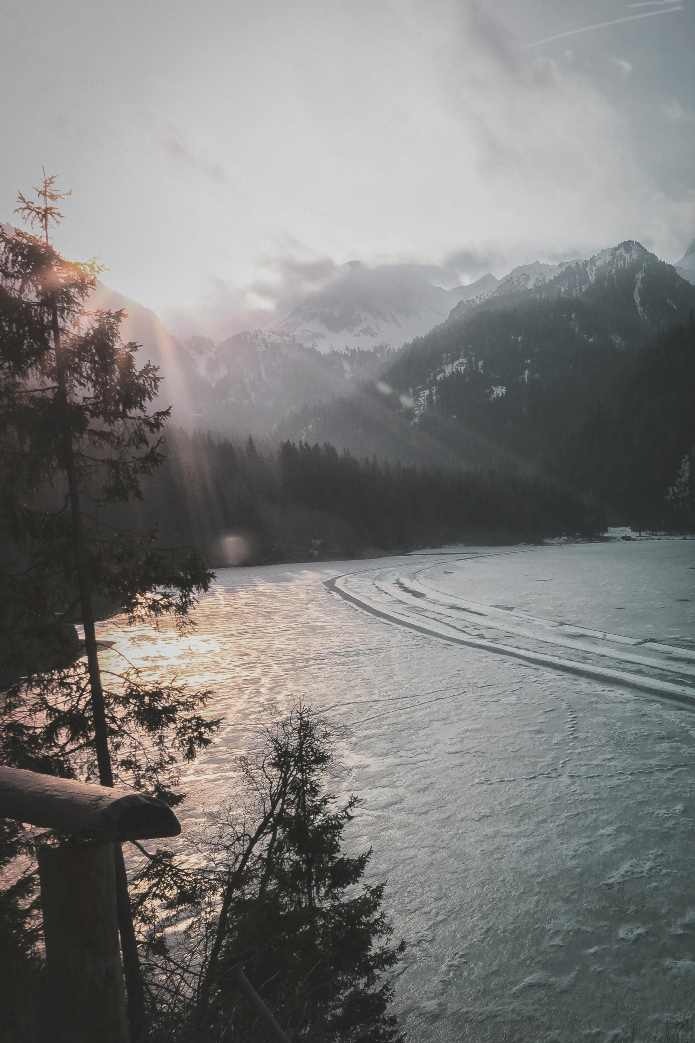 山湖景色宁静，树木沐浴在明媚的阳光下，远处山峰连绵