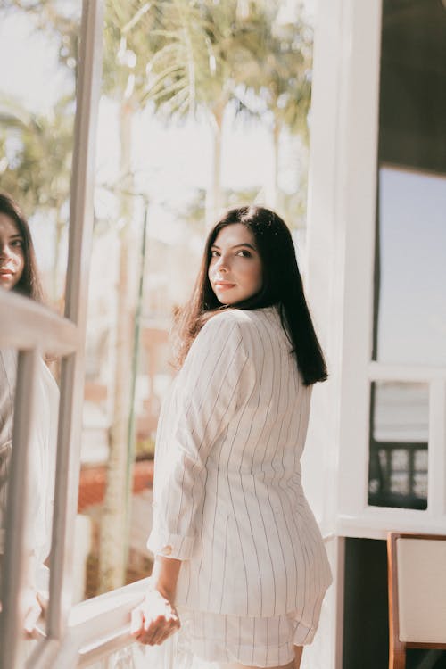 Free A woman in a white dress looking out the window Stock Photo