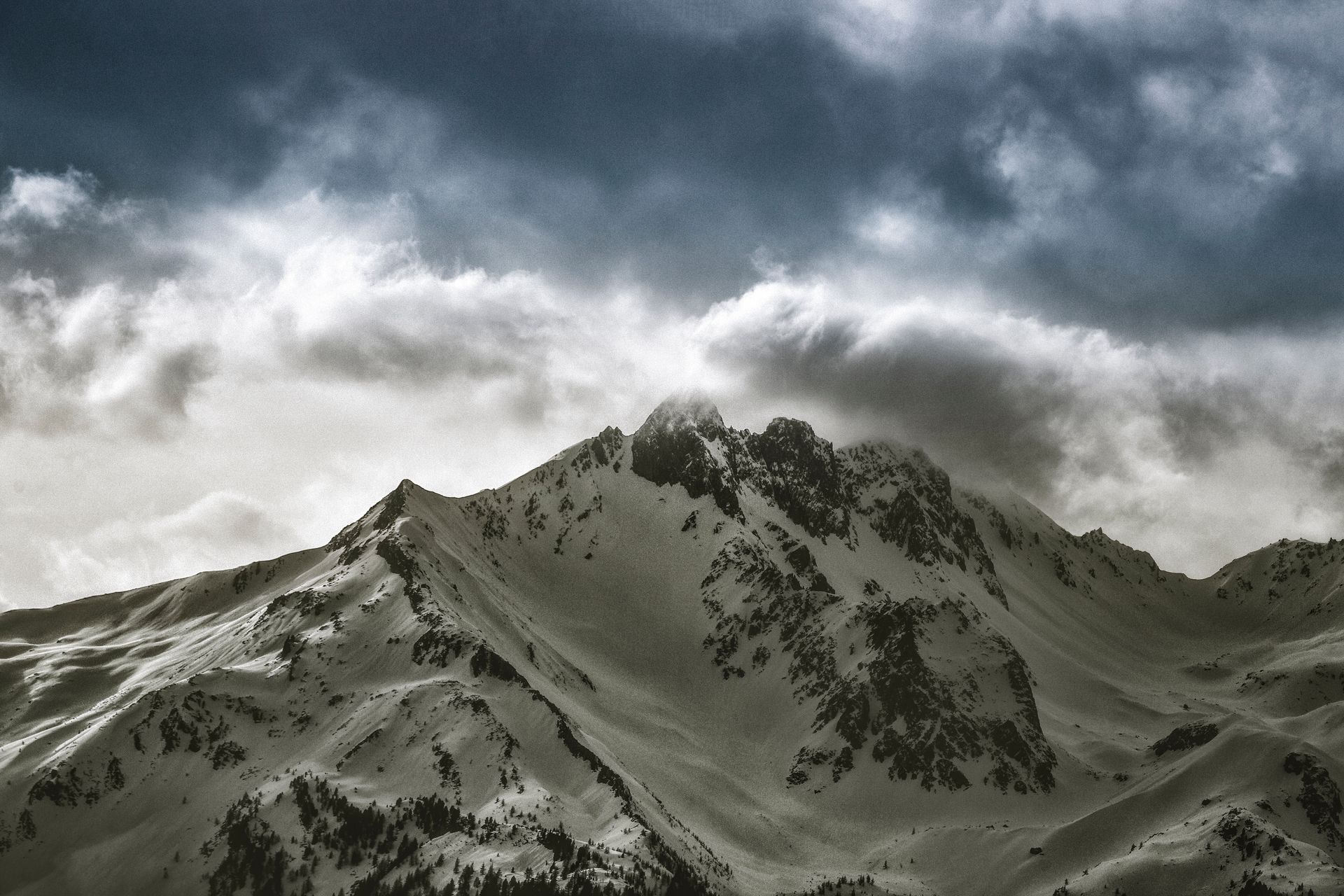 Breathtaking snowy mountain summit with moody sky, perfect for winter landscapes.