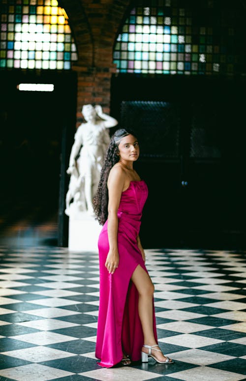 A woman in a pink dress posing in front of a black and white checkered floor