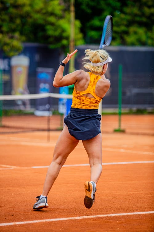 A woman in yellow and black tennis outfit swinging at a ball