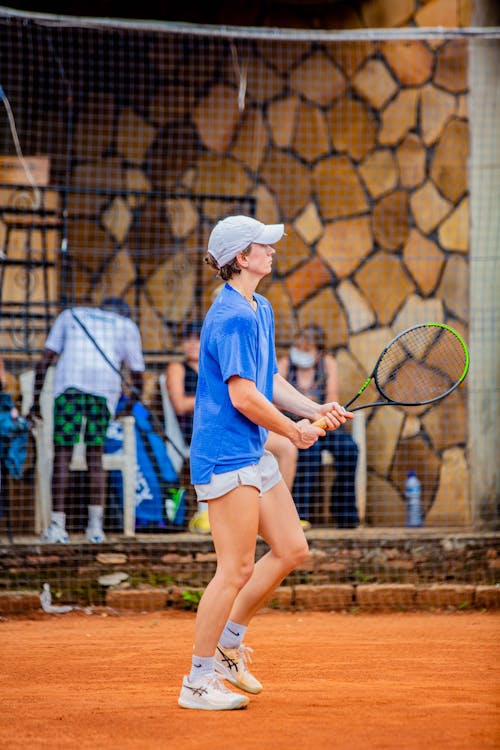 A young woman in blue shirt and shorts playing tennis