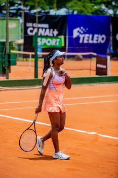 Confident female tennis player standing on a clay court during a match.