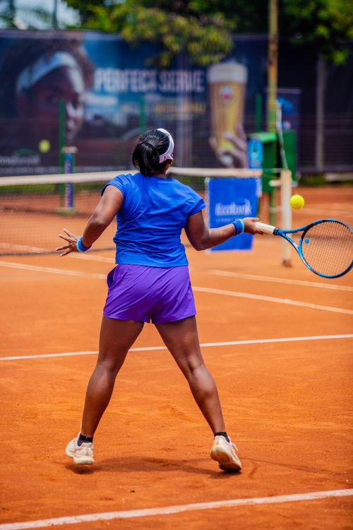 Free Back view of a female tennis player on a clay court during a sunny day match. Stock Photo