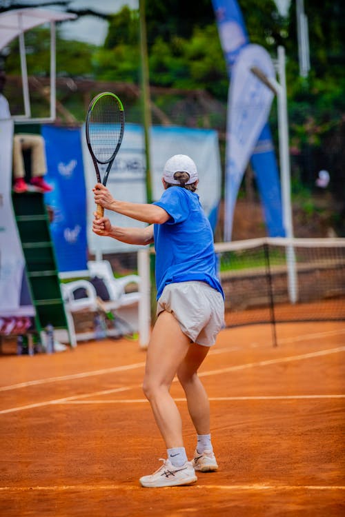 A woman in blue shirt and shorts playing tennis