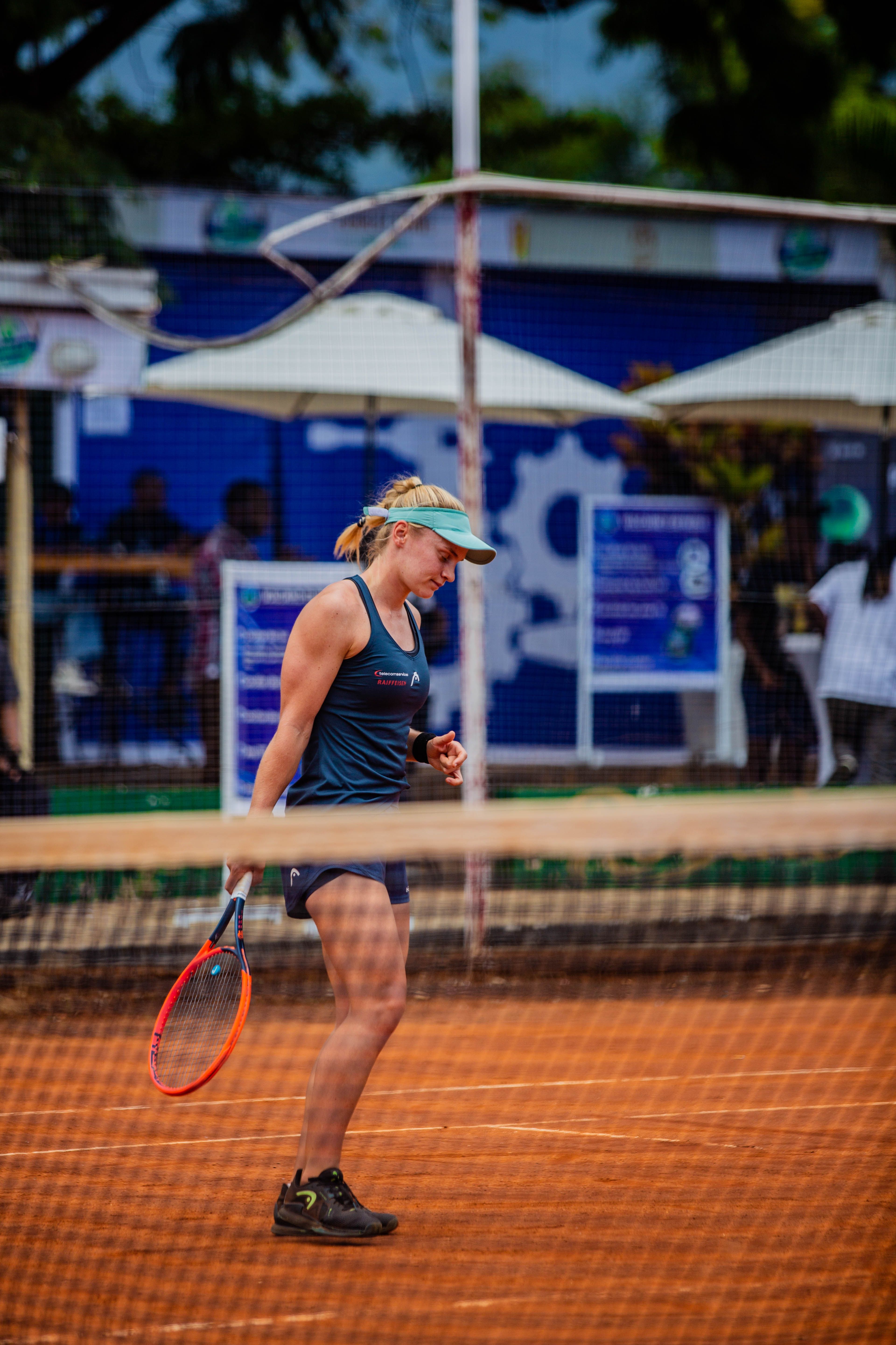 A determined female tennis player focuses intensely during a clay court match. 