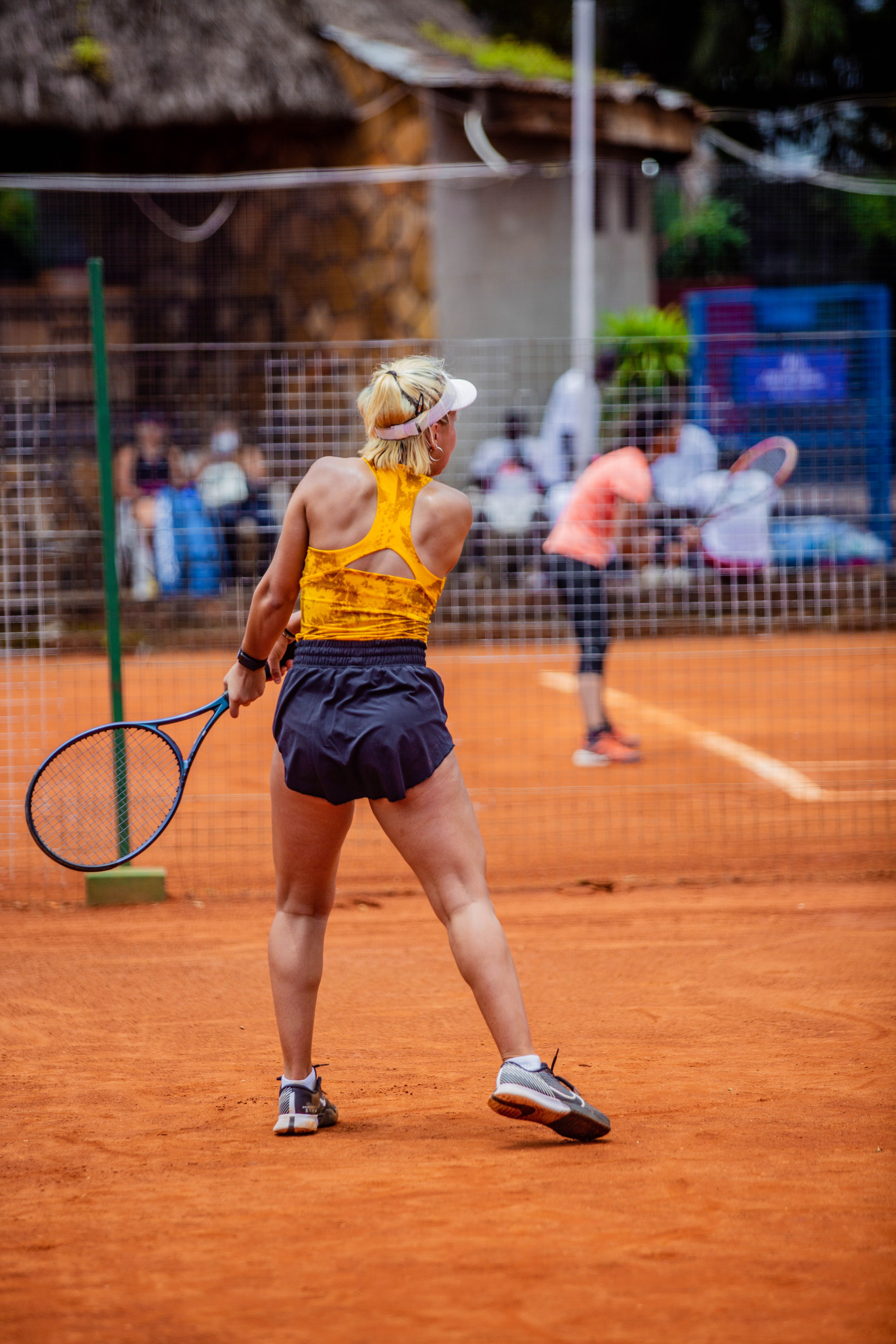 Women engage in an intense tennis match on a clay court.