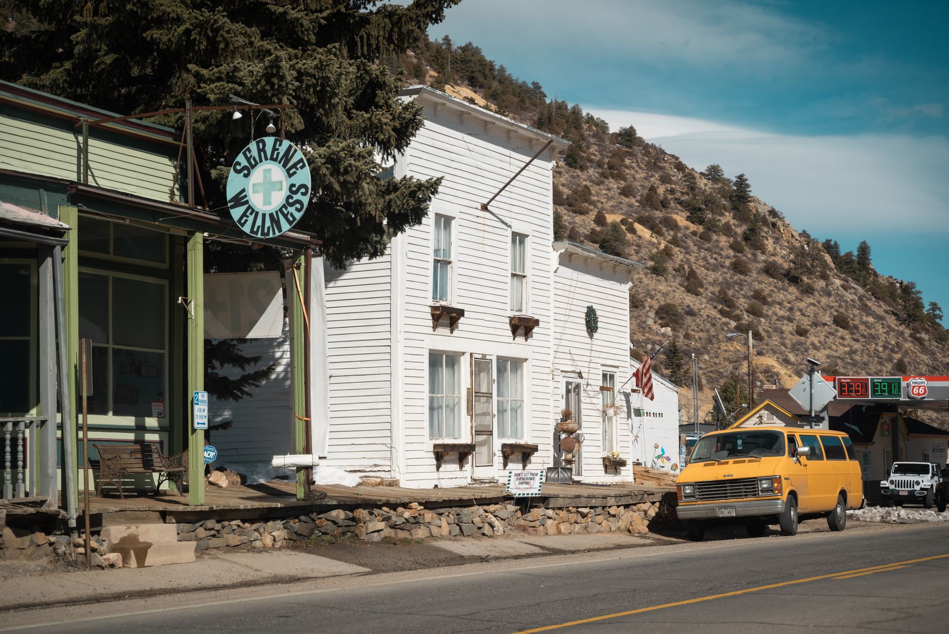 Capture of a small town street featuring a yellow truck and vintage buildings in daylight.