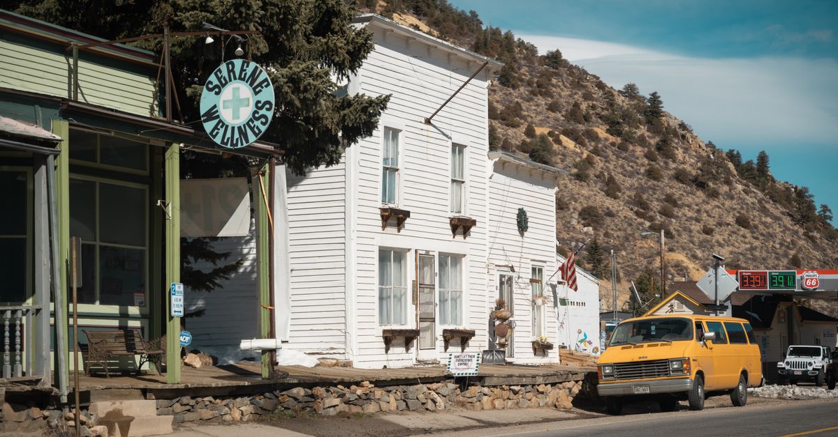 Capture of a small town street featuring a yellow truck and vintage buildings in daylight.