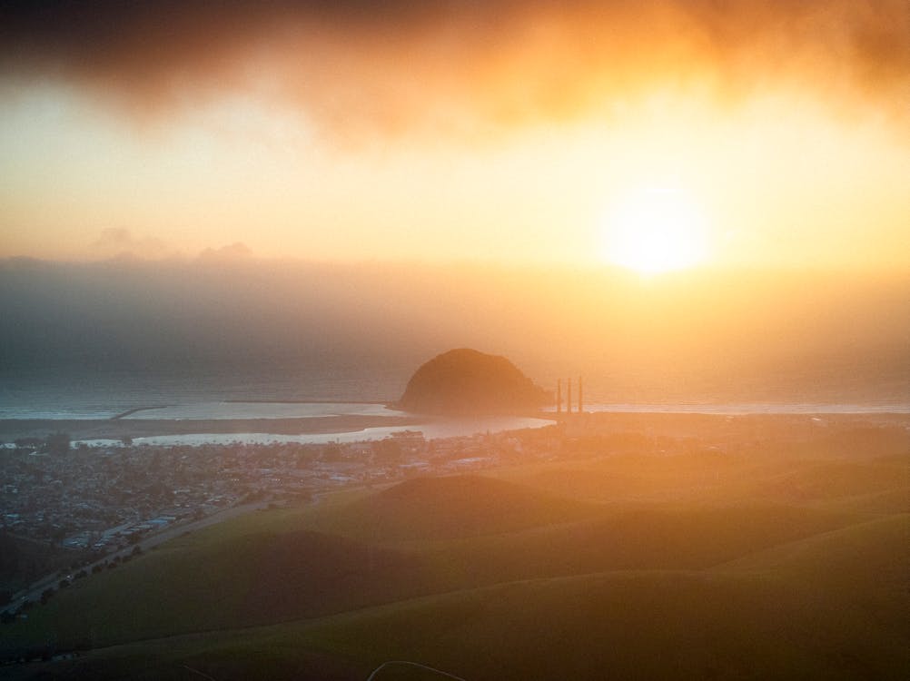 A sunrise over a foggy landscape with a hill in the distance