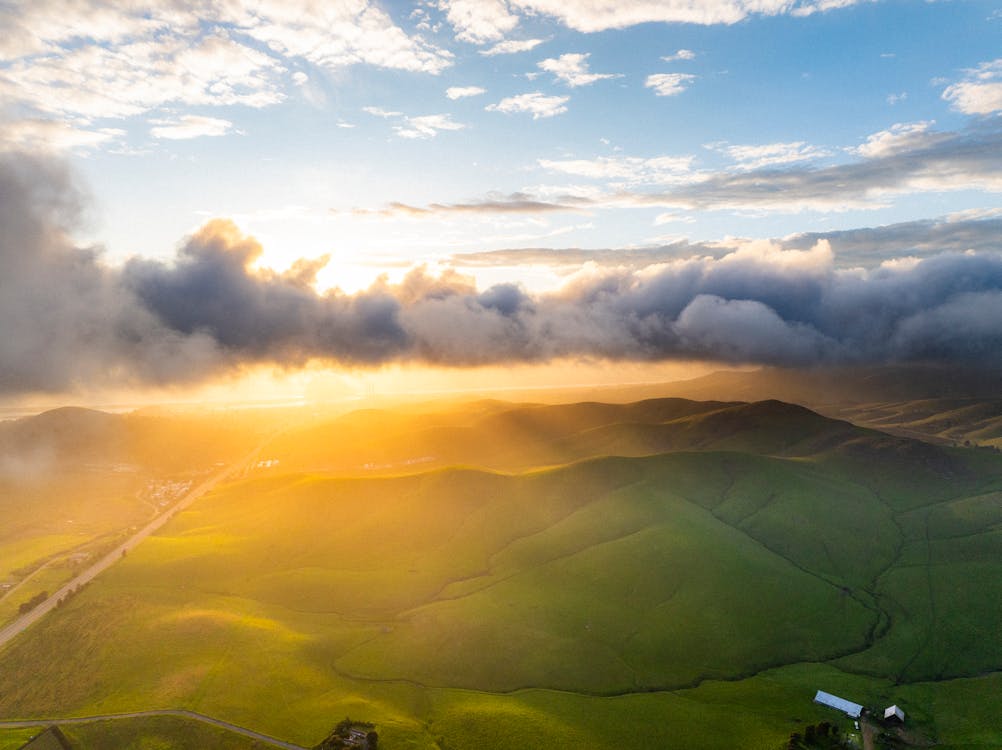 A sunset over a green valley with clouds