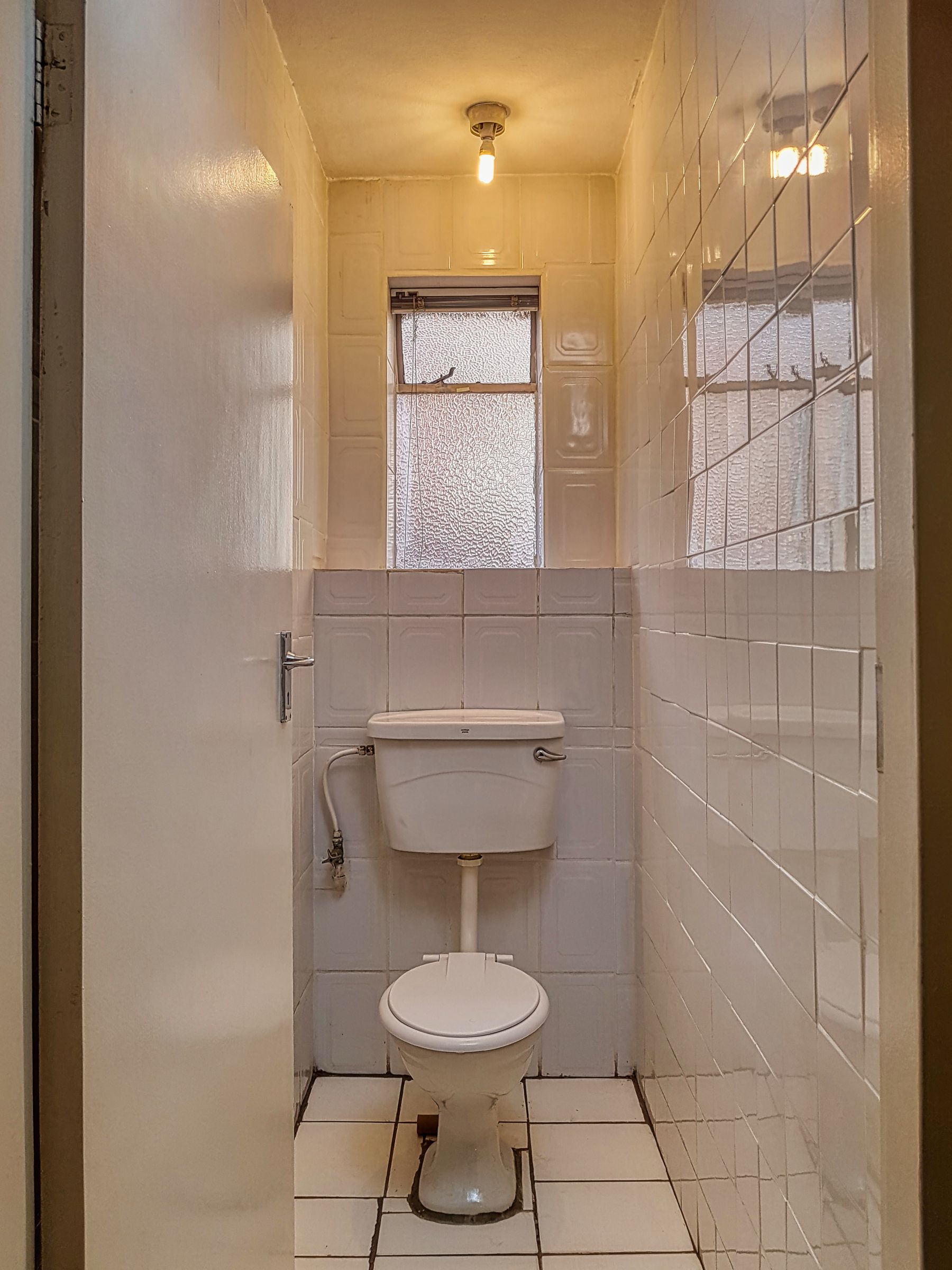 Small white bathroom with a window, wall-mounted toilet and compact fixtures