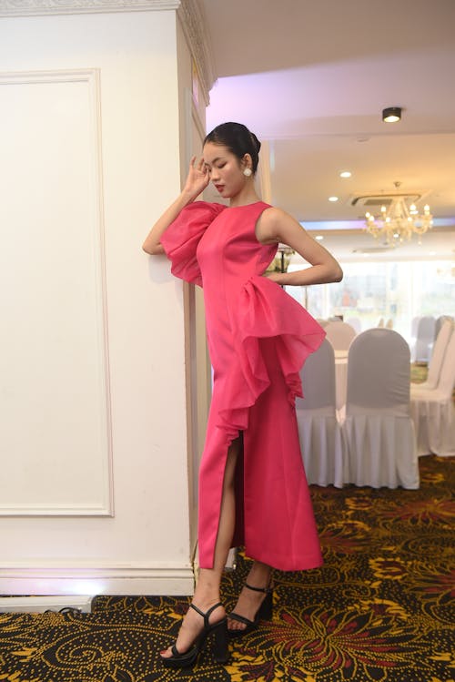 Elegant Woman in a Pink Dress and Heels Standing by the Wall 