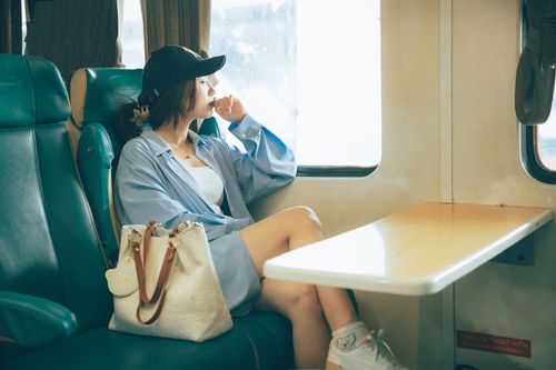 Free A young woman sits thoughtfully by a train window, contemplating life's journey. Stock Photo