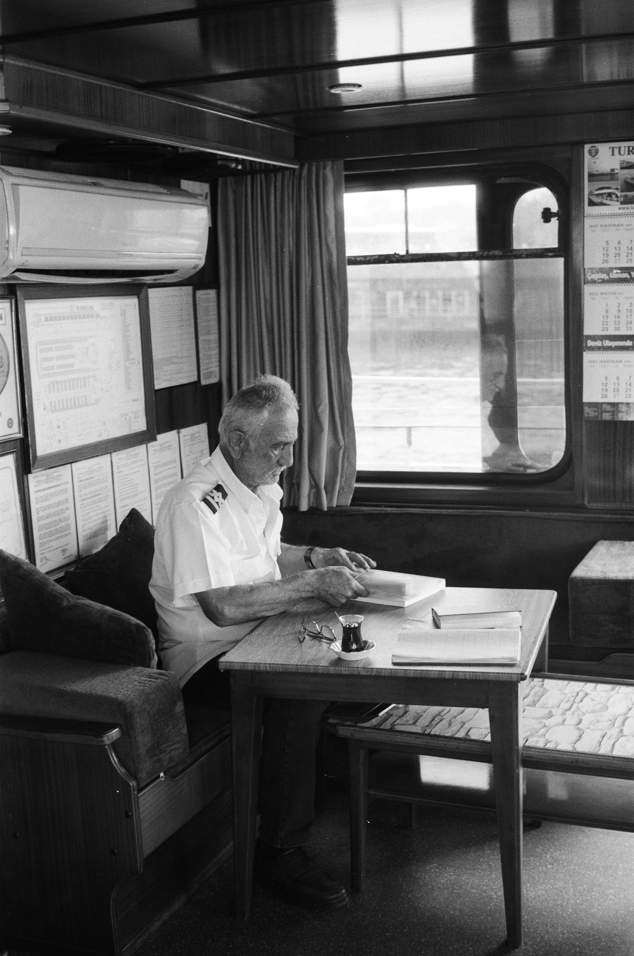 Ship captain reading a book inside a cabin in Istanbul.