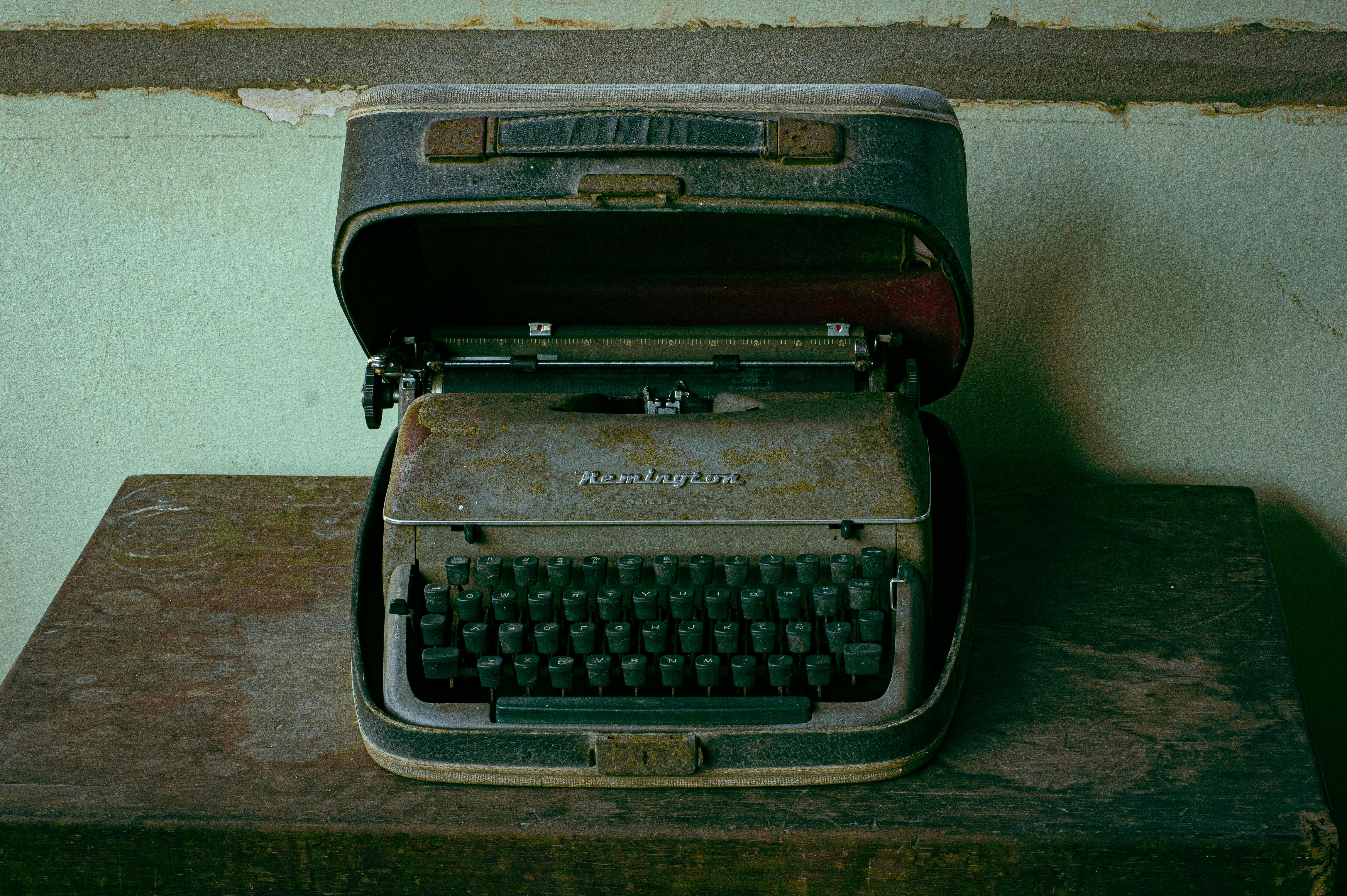 A rustic and nostalgic Remington typewriter in a weathered case on a wooden table.