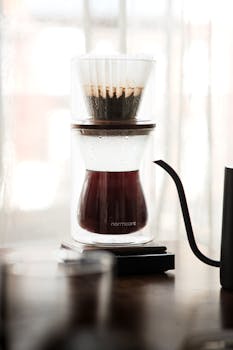 Glass dripper brewing fresh coffee in a stylish setup, perfect for a peaceful morning ritual.