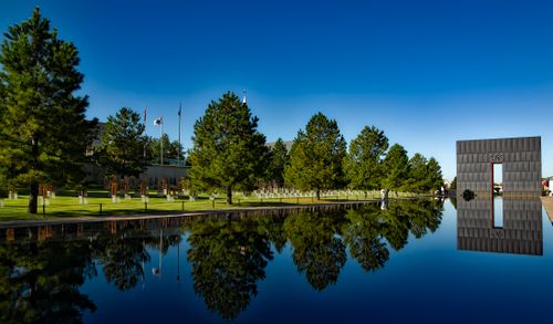 Free Serene memorial park with a monument and water reflection under clear blue sky. Stock Photo