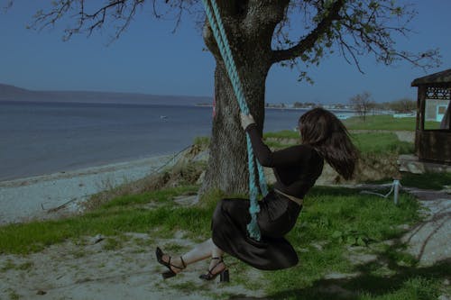 A woman swinging on a swing near a lake