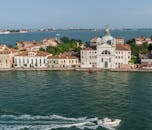 从鸟瞰视角看，一个宁静的岛屿上矗立着经典的威尼斯建筑，周围环绕着清澈的蓝色海水