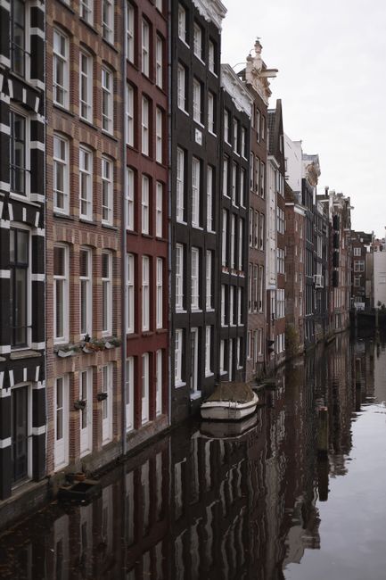 Elegant terraced houses lining the canal in Amsterdam, showcasing Dutch architecture.