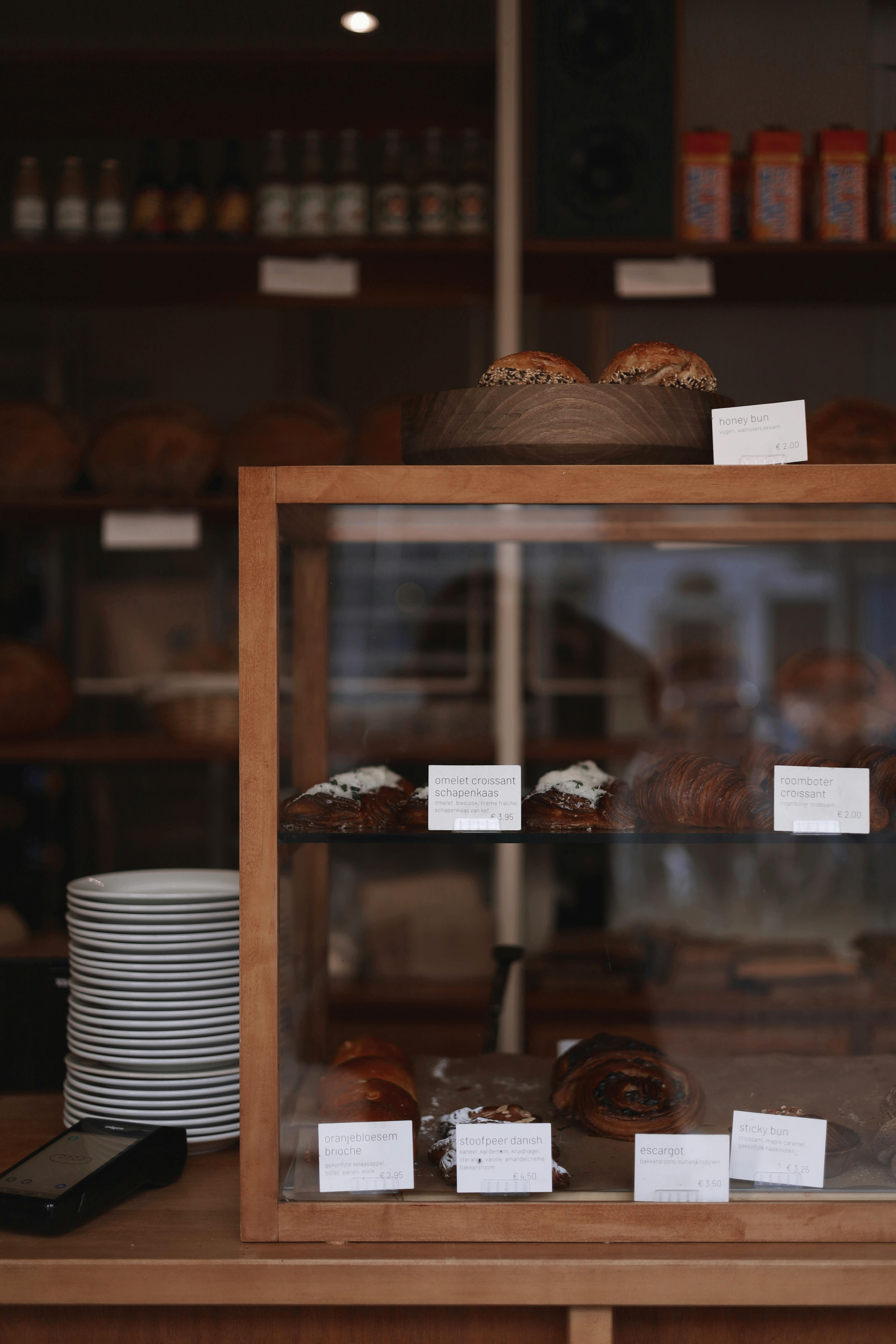 A quaint bakery in Amsterdam showcasing a delightful selection of fresh pastries behind a wooden counter.