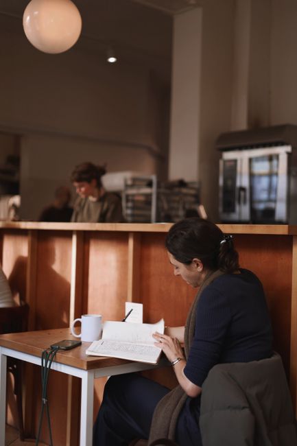 Woman engrossed in a book at an Amsterdam café. Warm ambiance, perfect for reading and relaxation.