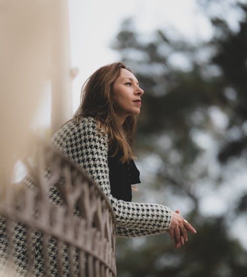 A woman in a checkered coat looking out over a railing