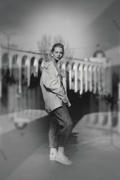 A woman in a jacket and jeans standing in front of a building