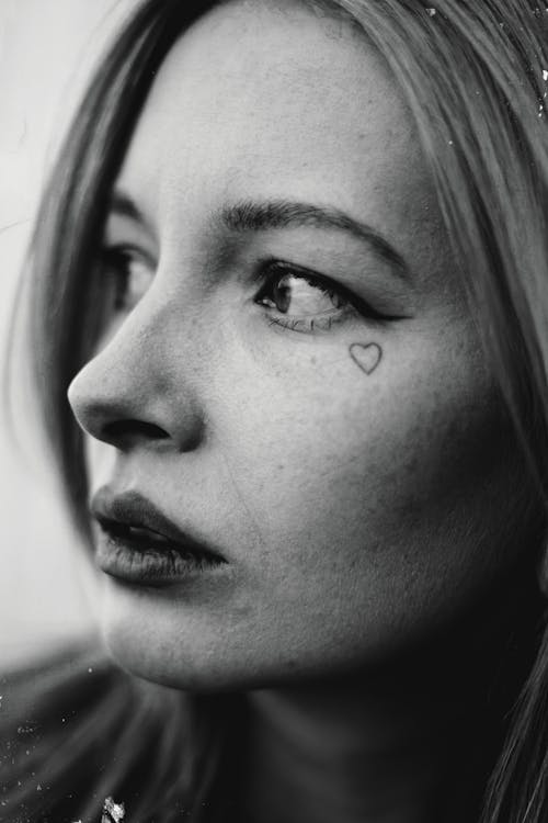 A black and white photo of a woman with a heart on her face