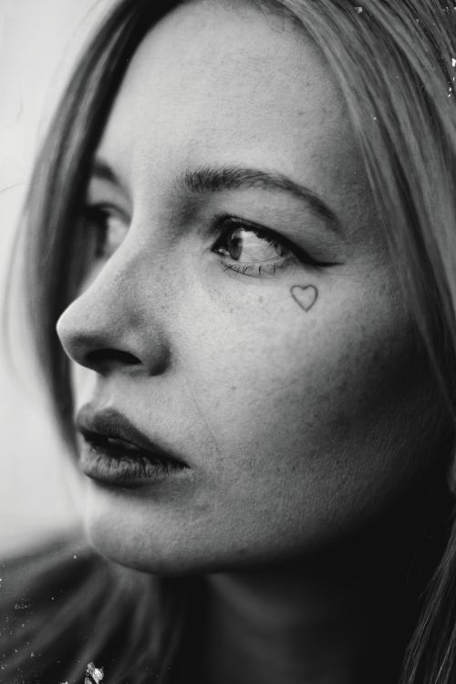 Free Close-up headshot of a woman with a heart tattoo under eye. Stock Photo