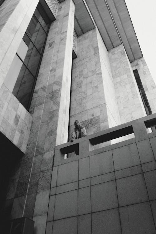 A black and white photo of a man standing on the side of a building