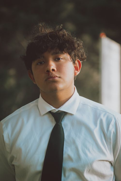 Free Teenage boy wearing a white shirt and tie, posing outdoors with a focused expression. Stock Photo