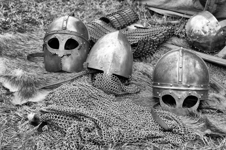 Grayscale Photography Of Chainmails And Helmets On Ground