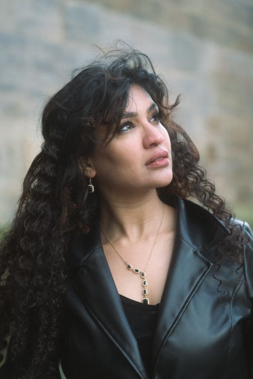 Free Chic portrait of a woman with curly hair in a black leather jacket, looking thoughtfully upward. Stock Photo