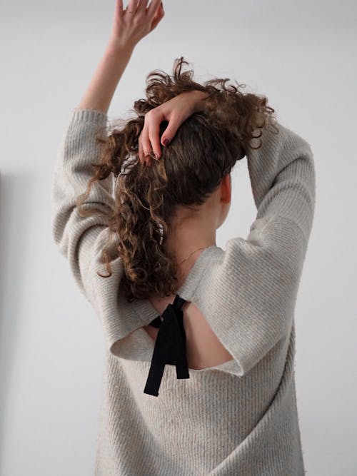 A woman with her hair in a bun is wearing a sweater